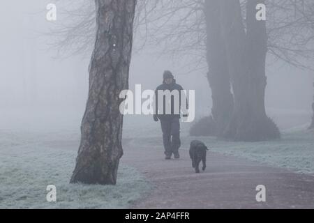 Chippenham, Wiltshire, UK. 21st Jan, 2020. As fog blankets many parts of the UK , a man is pictured walking a dog in a public park in Chippenham, Wiltshire. Credit: Lynchpics/Alamy Live News Stock Photo