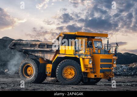 Big yellow mining truck laden anthracite moves open pit coal mine Stock Photo