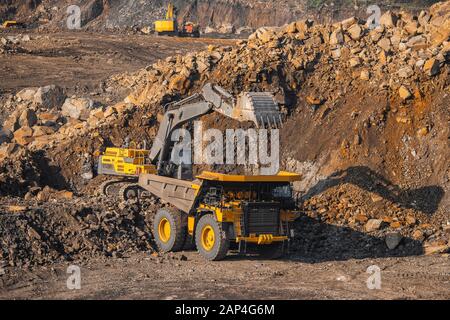 Open pit mine industry, excavator loading coal on big yellow mining truck for anthracite Stock Photo