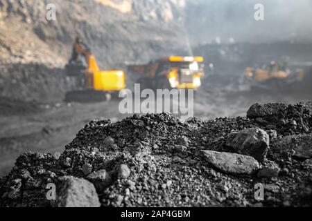 Coal open pit mine. In background blurred loading anthracite minerals excavator into large yellow truck Stock Photo