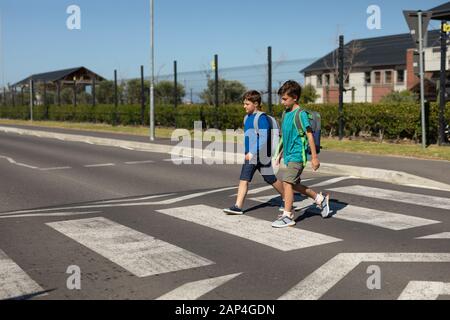 Two schoolboys crossing the road on a pedestrian crossing