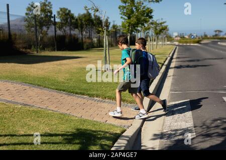 Two schoolboys reaching the pavement after crossing the road