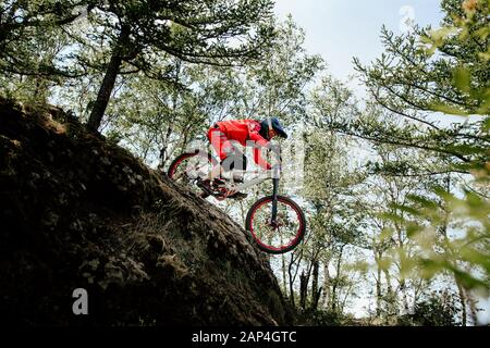 girl athlete rider downhill mountain biking. down mountain in forest trail Stock Photo