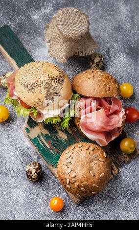 Fresh baked burger buns on a vintage wooden board. Dark moody food still life. Stock Photo