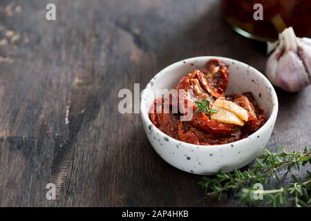 sun-dried tomatoes in a plate on a dark wooden background/ Stock Photo