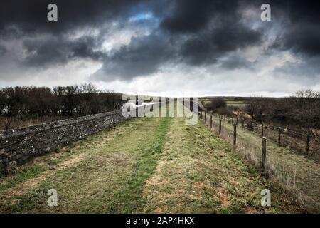 Dark rain clouds over the dam wall at Colliford Lake on Bodmin Moor in Cornwall. Stock Photo