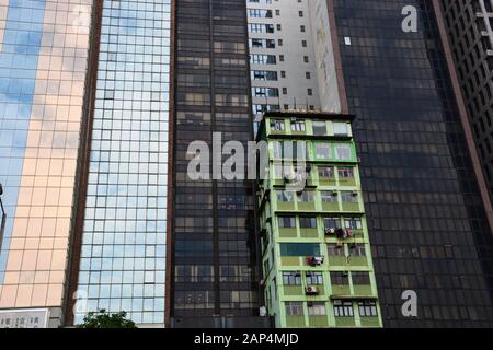 A holdout green apartment building is surrounded by new glass towers as the trendy neighborhood of Wan Chai undergoes gentrification in Hong Kong. Stock Photo