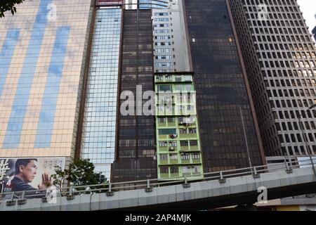 A holdout green apartment building is surrounded by new glass towers as the trendy neighborhood of Wan Chai undergoes gentrification in Hong Kong. Stock Photo