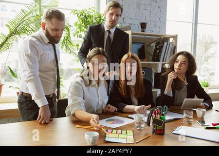 Positive. Group of young business professionals having a meeting. Diverse group of coworkers discussing new decisions, plans, results, strategy. Creativity, workplace, business, finance, teamwork. Stock Photo