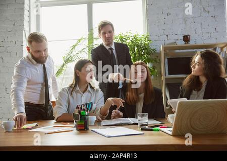 Positive. Group of young business professionals having a meeting. Diverse group of coworkers discussing new decisions, plans, results, strategy. Creativity, workplace, business, finance, teamwork. Stock Photo