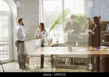 Second family. Group of young business professionals having a meeting. Diverse group of coworkers discuss new decisions, plans, results, strategy. Creativity, workplace, business, finance, teamwork. Stock Photo