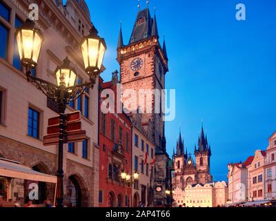 Prague, Old City Hall on the Town Square early evening, historic architecture of houses and church of St. Mary before Tyn illuminated with setting Sun Stock Photo