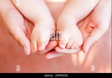 Close-up shot of father holding his child's feet in cupped hands. Shallow focus. Fatherhood parenting concept Stock Photo