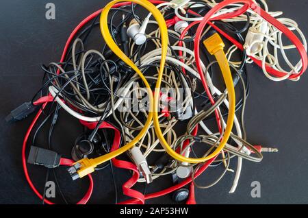 A lot of usb cables and wires on a dark background. Pile of colorful many used Cable cord Chargers, Wires Plug and USB. Reuse and Recycle concept. Stock Photo