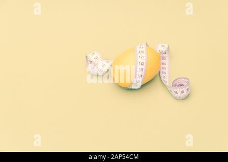 Lemon with measuring meter on yellow background. Healthy diet concept. Free copy space. Stock Photo