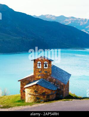 Picturesque view of stone chapel on Roselend lake coast (Lac de Roselend) in France Alps (Auvergne-Rhone-Alpes). Landscape photography Stock Photo