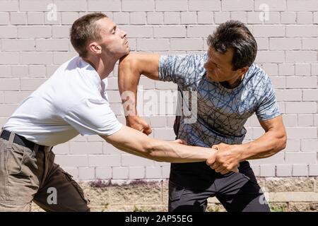 Mature male instructor strikes an elbow with an attacker.Close up.  Self Defense Techniques Krav Maga Stock Photo