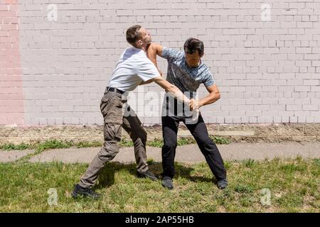 Mature male instructor strikes an elbow with an attacker. Self Defense Techniques Krav Maga Stock Photo