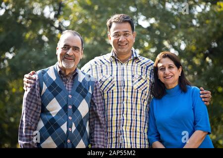 Man spending leisure time with senior parents at park Stock Photo