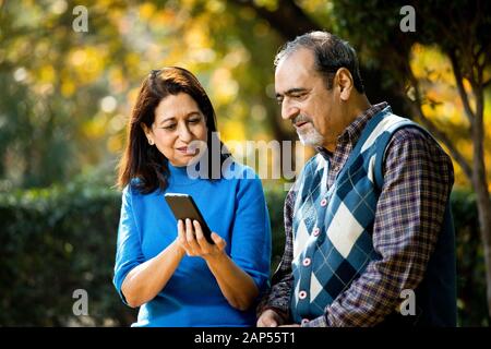 Senior woman sharing media content with her husband using mobile phone Stock Photo