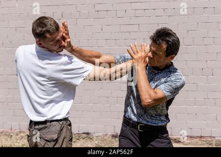 A mature male instructor strikes the attacker with a palm in his face. Close up. Self Defense Techniques Krav Maga Stock Photo