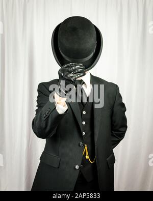 Portrait of Successful Man in Dark Suit and Leather Gloves Doffing Bowler Hat. Concept of Classic and Eccentric British Gentleman. Retro Fashion. Stock Photo