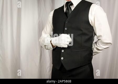 Butler or Waiter in Waistcoat or Vest and White Gloves Standing at Attention. Concept of Service Industry and Professional Hospitality and Courtesy. Stock Photo