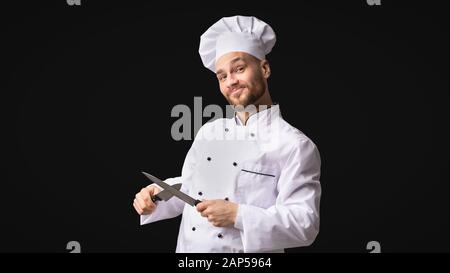 Funny Chef Man Sharpening Knives Standing, Studio Shot, Panorama Stock Photo