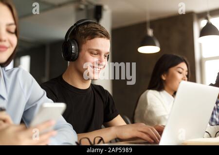 Smiling guy studying in college library, using laptop Stock Photo