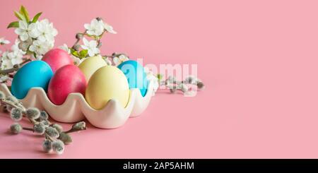 Colorful yellow eggs with spring flowers on pink. Easter. Spring. Close up. Space for text. Stock Photo