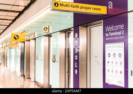 London, Heathrow Airport, Aug 2019: Yellow illuminated signs at airport. Entrance to a multi-faith prayer room. Faith symbols on door Stock Photo