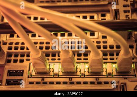 Network equipment is in the server room. Four internet twisted pair wires are connected to the router interfaces. Stock Photo