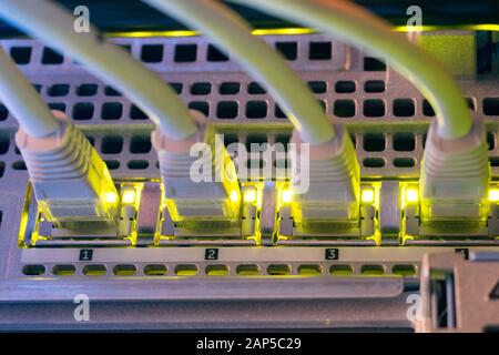 Four internet twisted pair wires are connected to the router interfaces. Network equipment is in the server room Stock Photo