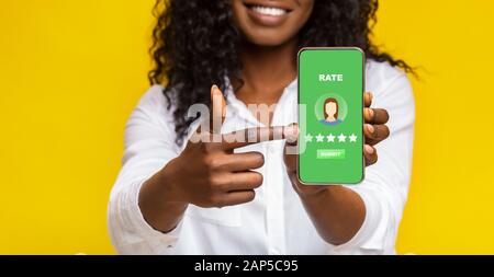 Unrecognizable Black Woman Pointing At Smartphone With Rating Application On Screen Stock Photo