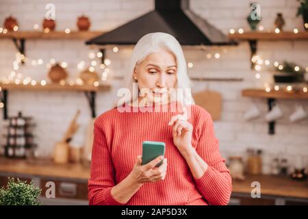 Beautiful elderly woman in red blouse looking thoughtful Stock Photo