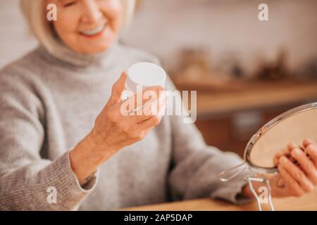 Grey-haired beautiful lady in grey blouse feeling good Stock Photo