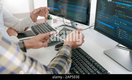 Young startup Programmers Sitting At Desks Working On Computers screen for Developing programming and coding to find solution to problem on New Applic Stock Photo