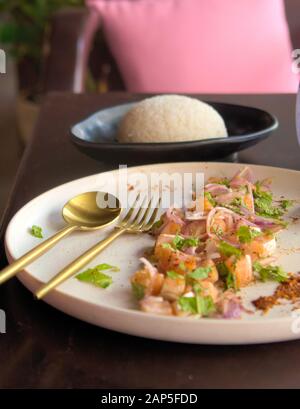 Asian cuisine. Diced raw salmon with red onions, lemon and mint, with steamed rice on the side. Close up shot. Stock Photo