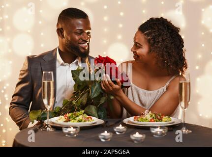 Handsome black guy giving beautiful flowers to his woman Stock Photo