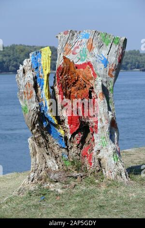 A rotten tree trunk on the riverbank. Someone has colored the log with different colors. There are also colored handprints. Stock Photo