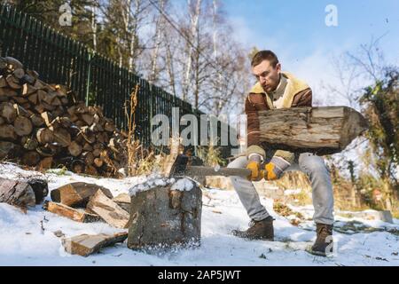 Man chopping wood with an axe, pieces and debris flying around Stock Photo