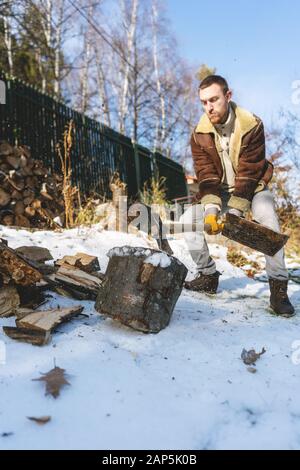 Man chopping wood with an axe, pieces and debris flying around Stock Photo