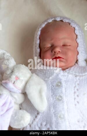 reborn baby doll holding a small toy laying on her back  selective focus to ad copy space Stock Photo
