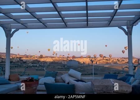 Cappadocia, Turkey: hot air balloons seen at dawn from a cozy terrace over the valley of Cavusin in the historical region in Central Anatolia Stock Photo