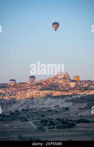 Cappadocia, Turkey, Europe: aerial view of Uchisar, ancient town of the historical region in Central Anatolia, with hot air balloons floating at dawn Stock Photo