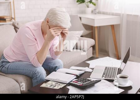 Old woman in despair counting finances at home Stock Photo