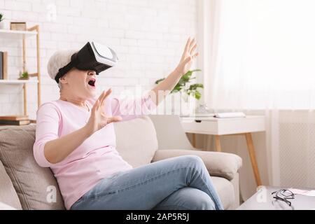 Amazed senior lady enjoying virtual reality in VR headset Stock Photo