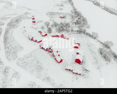 Scenic view of colorful wooden buildings top view. Fishing village and tourist town. Wooden red houses of fishing village in snowy covered in winter. Stock Photo