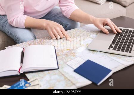 Senior woman choosing trip on map, booking hotel on laptop Stock Photo
