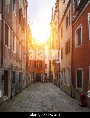 Street in Venice, Italy. Narrow street among old colorful brick houses in Venice, Italy. Venice postcard Stock Photo